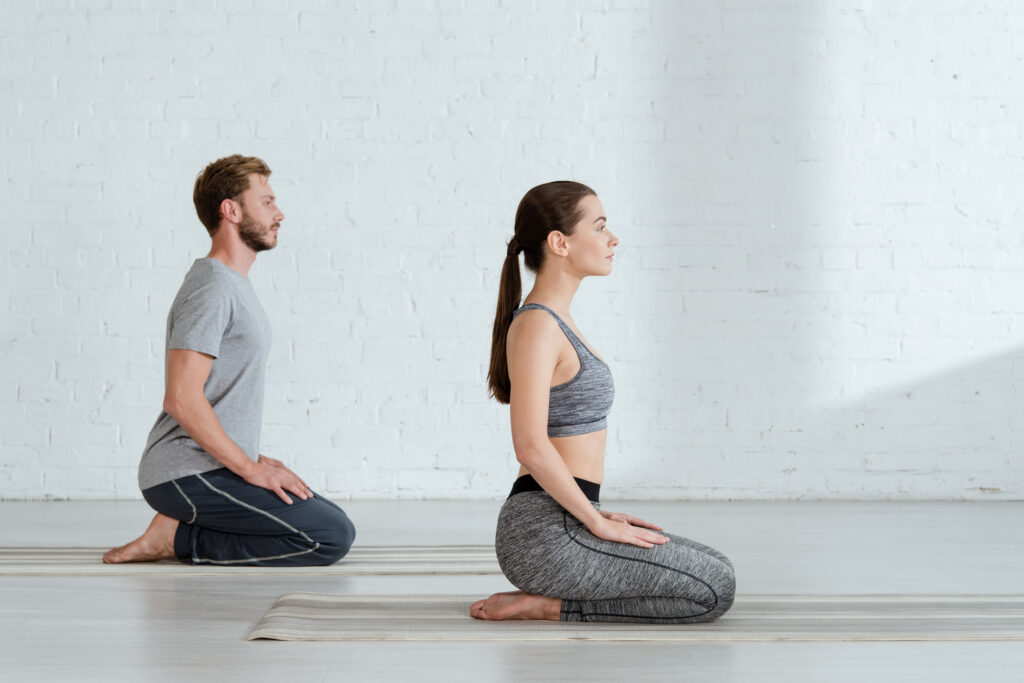 side view of young man and woman practicing yoga in