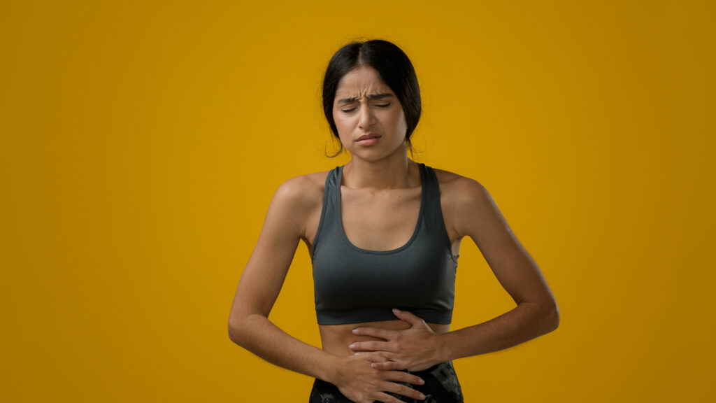 Sick Indian woman suffering from stomach ache holding belly feeling abdominal menstrual pain gastritis symptoms diarrhea discomfort painful periods inflammation of intestines food poisoning hunger