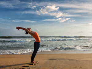 Young sporty fit woman doing yoga Sun salutation Surya Namaskar 