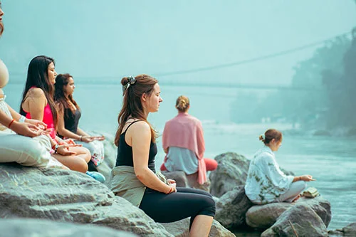 Students meditating near Ganga river